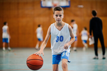 Naklejka premium Young player dribbling basketball on court