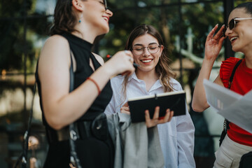 Three businesswomen having a casual meeting outdoors, discussing and sharing ideas. They are smiling and enjoying their conversation.