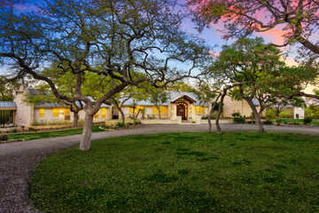 Charming residence with rustic architecture surrounded by lush trees at dusk in a serene landscape