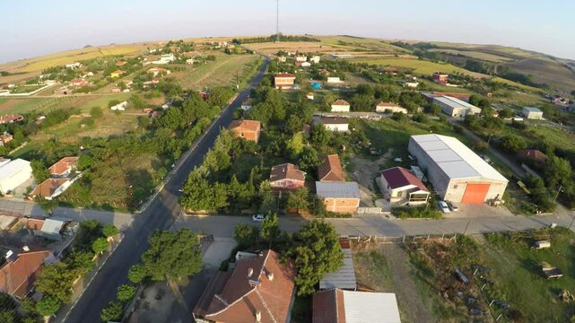 UAV Aerial. Yellow farming fields next to village. Rural road near village with golden oats field at sunset. Shot from above. Trakya Sarilar Village in the Thrace countryside in Turkey
