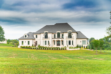Obraz premium Large modern country single family home with large lawn under blue skies.