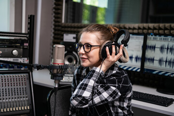 Portrait of a radio host working live in a radio studio with a microphone and headphones.