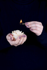 Female hands with manicure holding a candle and a lit match.