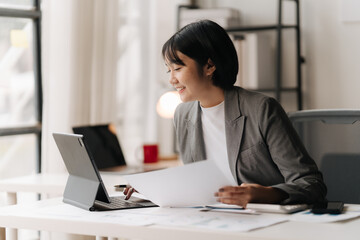 Focused and Confident: A young businesswoman in a modern office setting, engrossed in her work,...