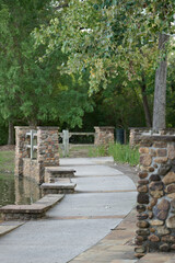 THE WOODLANDS, TEXAS - AUGUST 13th, 2024: Rob Fleming Park looks picturesque on a sunny day. The shimmering lake and fountain reflect beautifully, while stone and wooden structures add to its chic.