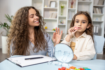 Child and doctor working on articulation and looking contented and concentrated