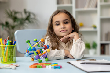 Cute girl sitting at the table while having a speech therapy tutorial and smiling nicely