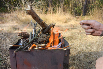 Lighting a fire in the grill, picnic in nature.