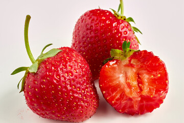 berries of ripe red strawberries with green stems isolated on white table