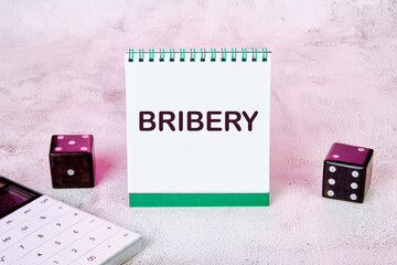 BRIBERY word written on a notepad on an abstract background