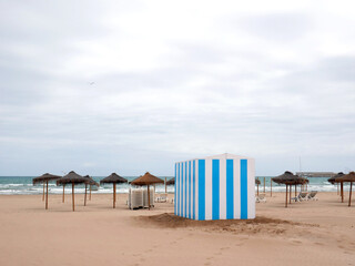 Quiet and relaxing beach with umbrellas striped blue and white ticket office