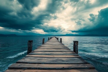 Obraz premium Wooden Pier Extending into Turquoise Ocean Under Dramatic Stormy Sky