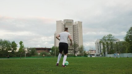 A young woman, dressed in a white t-shirt, black shorts, and white soccer socks, is practicing a Zidane Roulette on a grassy field. The action is dynamic, showing her athleticism and control