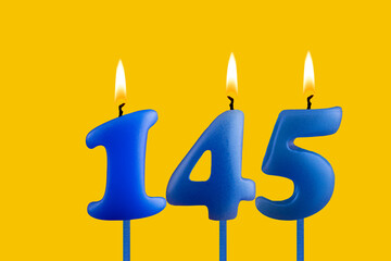 Blue candle number 145 - Birthday on yellow background