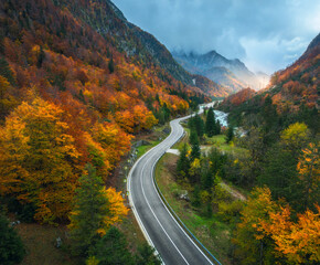 Aerial view of curvy road and orange forest in mountains in fall