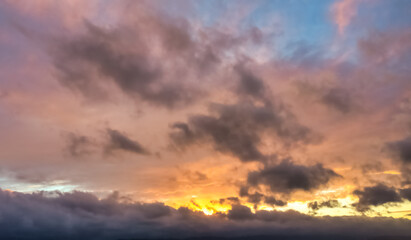 A beautiful sky tinted by the sun leaving vibrant shades of gold, pink, blue and multicolored. Clouds in the twilight evening and morning sky. Cloudy sky background in the evening, and during the day.