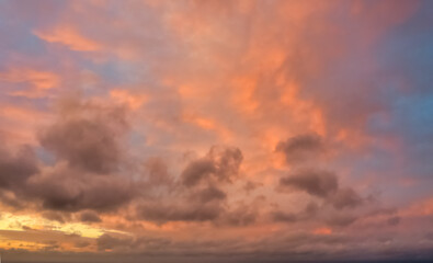 A beautiful sky tinted by the sun leaving vibrant shades of gold, pink, blue and multicolored. Clouds in the twilight evening and morning sky. Cloudy sky background in the evening, and during the day.