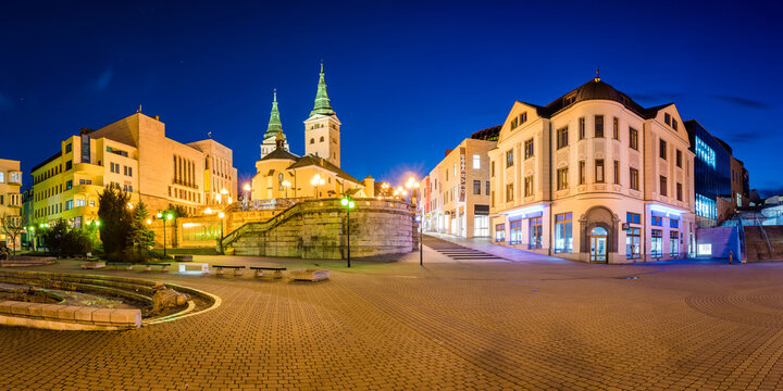 Žilina, Slovakia -  03.17.2019: Žilina city centre during blue hour - Andrej Hlinka Square - Holy Trinity Cathedral, Mirage Commerce Complex Center, Municipal theatre