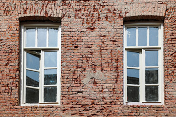 Two vintage windows on brick wall  in  urban setting 