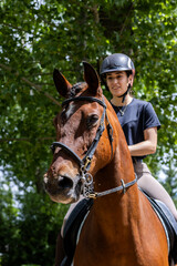 Fototapeta premium A woman is riding a brown horse with a black bridle