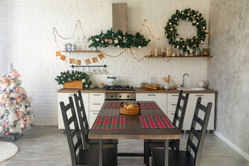 Festive winter cozy kitchen interior with garlands, decorations and gifts. Christmas dinner at the decorated table. Modern Kitchen Interior in New Luxury Home Decorated in Christmas Style