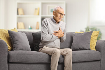 Obraz premium Elderly man suffering heart attack on a sofa
