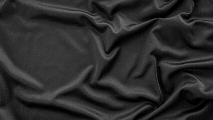 A detailed close-up of black fabric with natural creases and folds, capturing its smooth texture and subtle sheen. Ideal for fashion, fabric patterns, or background designs