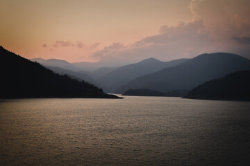Twilight Calm: Sunset Over Lake and Mountain Silhouettes