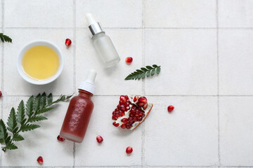 Composition with bottles of essential oil, honey, pomegranate and fern leaves on light tile background © Pixel-Shot
