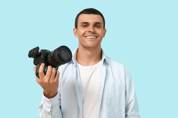 Obraz premium Portrait of male photographer with modern camera on blue background