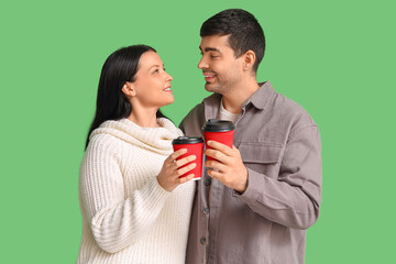 Young couple with cups of mulled wine on green background