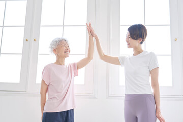 Obraz premium ハイタッチをするスポーツウェアを着た高齢者の女性とミドルエイジの女性