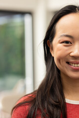 Smiling young asian woman with long hair, wearing red shirt, looking at camera, copy space