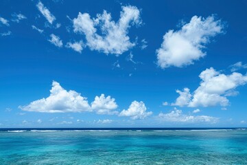 Obraz premium Clear Blue Sky with White Clouds Over Calm Turquoise Ocean Waters