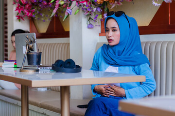 Beautiful young Asian woman wearing a hijab feeling unwell, having a stomachache because of eating...