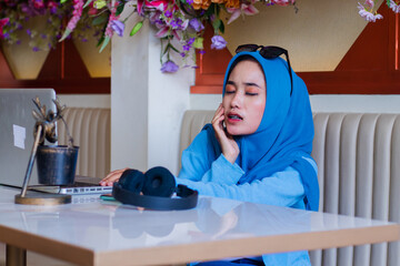portrait of beautiful adult asian girl wearing hijab covering eyes uncomfortable body toothache...