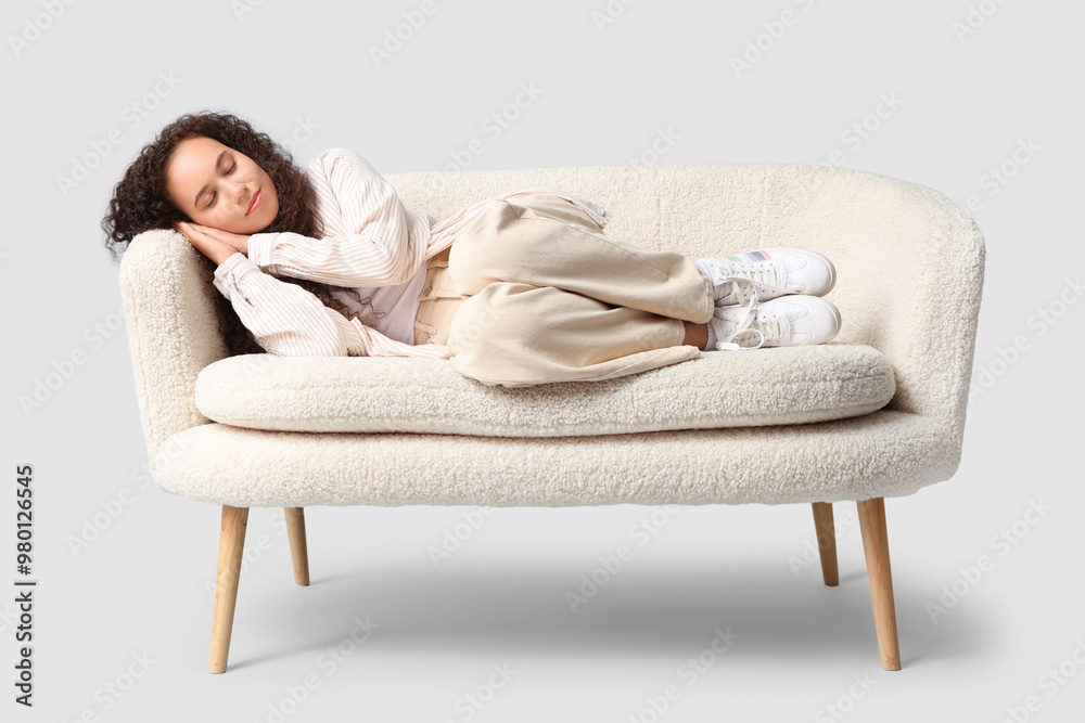 Wall mural beautiful young happy african-american woman sleeping on sofa against grey background