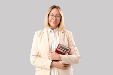 Mature female math teacher with calculator on grey background