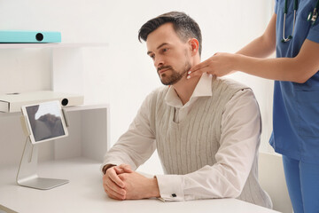 Fototapeta premium Female doctor checking man's pulse in clinic