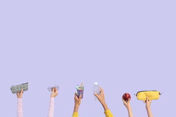 Children with school supplies, apple and water bottle on lilac background