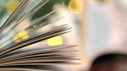 Christmas tales, stories, myths and legends.open book foreground and reading woman with book soft focus on shining fir tree background. Books on Christmas and winter themes. 4k footage