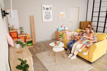 Cute little children with their mother watching cartoons on TV at home