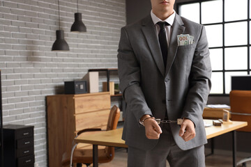 Handcuffed businessman with bribe in office. Corruption concept