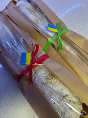 Two delicious strudels, dusted with powdered sugar, are wrapped in translucent packaging and tied with colorful ribbons—one red and one green. The packages are adorned with small Ukrainian flags.