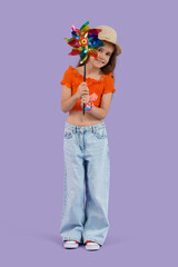 Little girl with toy windmill on lilac background