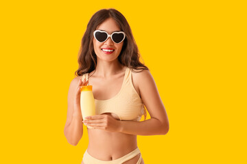 Young Asian woman in sunglasses with sunscreen cream on yellow background
