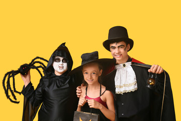 Kids dressed for Halloween with gift bag on yellow background