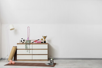 Interior of light room with commode and sports equipment