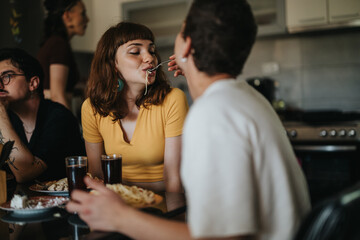 A group of friends share a joyful meal in a warm kitchen, highlighting togetherness and friendship. The scene captures a playful moment, emphasizing comfort and connection.