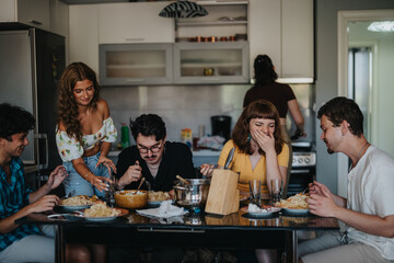 A lively group of friends shares a meal in a cozy kitchen setting. Laughter and joy fill the room...